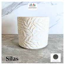 Load image into Gallery viewer, Silas White ceramic planter with leaf pattern on a gray surface, branded 'LEAFERIE'.