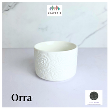 Load image into Gallery viewer, Orra White ceramic pot with textured design on a light gray background, featuring the brand 'LEAFERIE'.