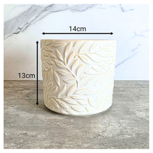 Load image into Gallery viewer, Silas White ceramic planter with leaf pattern on a gray surface, branded 'LEAFERIE'.
