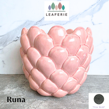 Load image into Gallery viewer, A pink ceramic planter with a textured, scaled leaf-like pattern, labeled 'Runa' by the brand LEAFERIE, set against a white marble background.