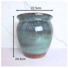 Load image into Gallery viewer, A glazed ceramic planter pot with a speckled green and brown finish, shown with black dimension arrows indicating a height of 24.5cm and a width of 22.