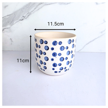 Load image into Gallery viewer, Cirra White ceramic planter with blue dot pattern on a light gray background, featuring the brand 'LEAFAERIE'.