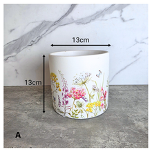 Load image into Gallery viewer, The Leaferie Rhea Two ceramic planters with floral designs on a marble surface, featuring the brand 'LEAFERIE'.