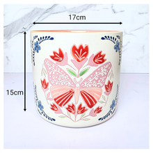 Load image into Gallery viewer, Bloomie Ceramic pot with floral and butterfly design on a marble background, featuring the brand 'LEAFERIE'.