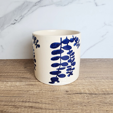 Load image into Gallery viewer, The Leaferie Hamsa blue petals on white ceramic pot.