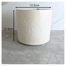 Load image into Gallery viewer, Otis White ceramic planter with floral patterns on a gray surface, featuring the LEAFERIE brand.