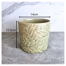 Load image into Gallery viewer, Nyra Green ceramic planter with leaf pattern on a gray surface, featuring the Leaferie brand.