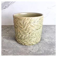 Load image into Gallery viewer, Nyra Green ceramic planter with leaf pattern on a gray surface, featuring the Leaferie brand.