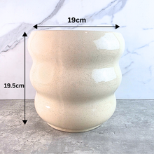 Load image into Gallery viewer, A ceramic planter pot with a wavy, ribbed design in a speckled cream-beige glaze, shown with dimension overlays indicating a height of 19.5cm and a top diameter of 19cm against a marble-patterned background.