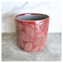 Load image into Gallery viewer, Talia Red ceramic planter with leaf pattern on a gray surface, branded 'LEAFERIE'.