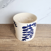 Load image into Gallery viewer, The Leaferie Hamsa blue petals on white ceramic pot.