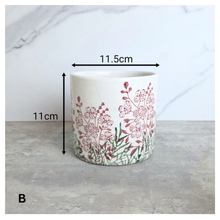 Load image into Gallery viewer, Lumelle Ceramic planter with floral design on a gray surface, featuring the brand 'LEAVERIE'.