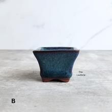 Load image into Gallery viewer, Blue ceramic pot on a light gray surface with 'The Leafeorie' branding.