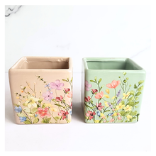 Load image into Gallery viewer, Two square ceramic planters with floral designs on a white background