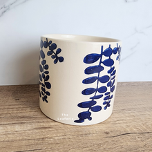 Load image into Gallery viewer, The Leaferie Hamsa blue petals on white ceramic pot.