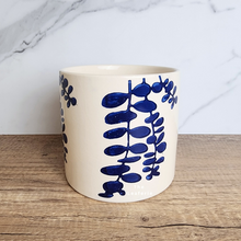 Load image into Gallery viewer, The Leaferie Hamsa blue petals on white ceramic pot.