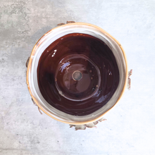 Load image into Gallery viewer, Top-down view of a round ceramic bowl with a glossy dark brown interior, a light beige rim, and a rustic bark edge, set against a textured gray concrete background.