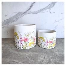 Load image into Gallery viewer, The Leaferie Rhea Two ceramic planters with floral designs on a marble surface, featuring the brand 'LEAFERIE'.