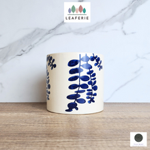 Load image into Gallery viewer, The Leaferie Hamsa blue petals on white ceramic pot.

