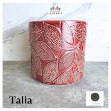 Load image into Gallery viewer, Talia Red ceramic planter with leaf pattern on a gray surface, branded 'LEAFERIE'.
