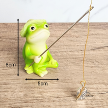 Load image into Gallery viewer, Green frog figurine holding a fishing rod with measurements and a leaf-shaped pendant on a wooden surface.
