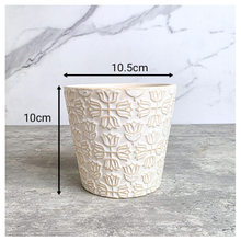 Load image into Gallery viewer, An off-white ceramic planter with a textured, embossed floral pattern, displayed on a gray stone surface against a white marble background. The brand name 'LEAFERIE' is visible at the top, and the product name 'Colette' is shown at the bottom left.
