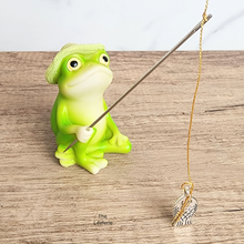 Load image into Gallery viewer, Green frog figurine holding a fishing rod with a gold chain and silver bird charm on a wooden surface.
