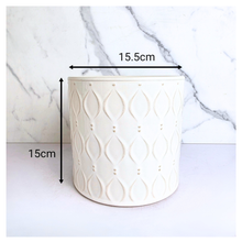 Load image into Gallery viewer, An off-white ceramic planter with a textured geometric leaf pattern, shown against a white marble background. The brand name 'LEAFERIE' is visible at the top, and the product name 'Oriva' is displayed at the bottom left.
