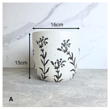 Load image into Gallery viewer, A speckled off-white ceramic planter with black botanical leaf patterns, shown with dimension overlays indicating a width of 16cm and a height of 15cm against a marble-patterned background.
