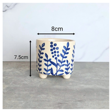 Load image into Gallery viewer, A small ceramic planter with a cream-colored glaze and blue floral botanical pattern, shown with dimension overlays indicating a height of 7.5cm and a width of 8cm.
