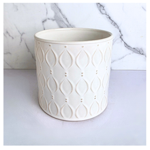Load image into Gallery viewer, An off-white ceramic planter with a textured geometric leaf pattern, shown against a white marble background. The brand name 'LEAFERIE' is visible at the top, and the product name 'Oriva' is displayed at the bottom left.
