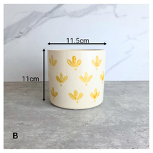 Load image into Gallery viewer, Romy Two ceramic planters with yellow patterns on a gray surface, branded 'LEAFERIE'.
