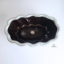 Load image into Gallery viewer, Black ceramic planter with scalloped edge on a white background, branded &#39;The Leaferie&#39;.
