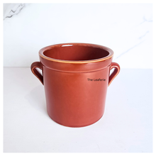 Load image into Gallery viewer, Terracotta pot with handles on a white background, branded &#39;The Leaferie&#39;.
