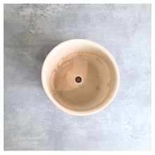 Load image into Gallery viewer, An off-white ceramic planter with a blue hand-painted pattern of stylized flowers, displayed on a gray surface against a white marble background. The brand LEAFERIE is visible at the top, and the name 'Zorina' is shown at the bottom left.
