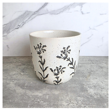 Load image into Gallery viewer, A speckled cream ceramic planter with black botanical leaf patterns, set on a gray stone surface against a white marble background.
