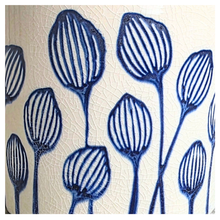 Load image into Gallery viewer, An off-white ceramic planter with a blue hand-painted pattern of stylized flowers, displayed on a gray surface against a white marble background. The brand LEAFERIE is visible at the top, and the name 'Zorina' is shown at the bottom left.
