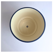 Load image into Gallery viewer, Top-down view of a round ceramic planter pot with a cream-colored interior, a dark navy blue rim, and a small drainage hole in the center.
