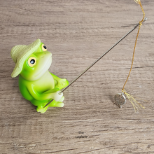 Load image into Gallery viewer, Green frog figurine with a fishing rod on a wooden surface
