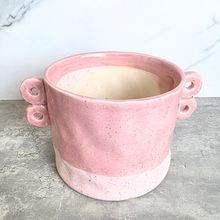 Load image into Gallery viewer, A pink speckled ceramic planter with two loop handles on the sides, shown on a gray stone surface against a white marble background. The brand name LEAFERIE is displayed at the top, and the color name 'Kova' along with a texture swatch graphic are shown in the corners.
