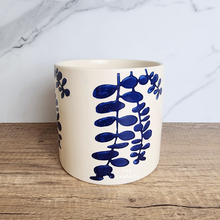 Load image into Gallery viewer, The Leaferie Hamsa blue petals on white ceramic pot.

