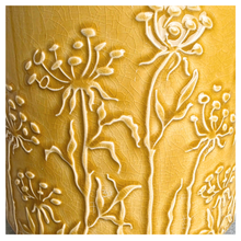 Load image into Gallery viewer, A yellow glazed ceramic planter with embossed wildflower patterns, displayed on a gray stone surface against a white marble background. The brand LEAPERIE is visible at the top, and the product name 'Avara' is shown at the bottom left.
