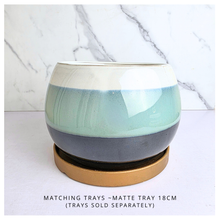 Load image into Gallery viewer, A ceramic round tray with a three-tone glazed finish in cream, mint green, and charcoal gray, resting on a round gold-colored saucer. The image is set against a white marble-patterned background with text at the bottom stating 'MATCHING TRAYS - MATTE TRAY 18CM (TRAYS SOLD SEPARATELY)'.
