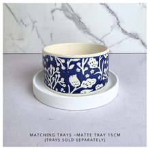 Load image into Gallery viewer, A ceramic bowl with a navy blue and white floral pattern sits on a round white tray, set against a light gray surface with a white marble backsplash. Text at the bottom reads 'MATCHING TRAYS - MATTE TRAY 15CM (TRAYS SOLD SEPARATELY)'.
