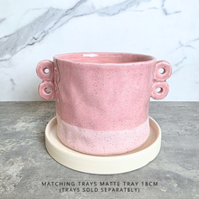 Load image into Gallery viewer, A pink speckled ceramic planter with two loop handles on the sides, shown on a gray stone surface against a white marble background. The brand name LEAFERIE is displayed at the top, and the color name 'Kova' along with a texture swatch graphic are shown in the corners.
