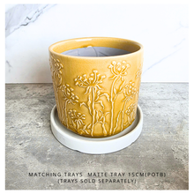 Load image into Gallery viewer, A yellow glazed ceramic planter with embossed wildflower patterns, displayed on a gray stone surface against a white marble background. The brand LEAPERIE is visible at the top, and the product name 'Avara' is shown at the bottom left.
